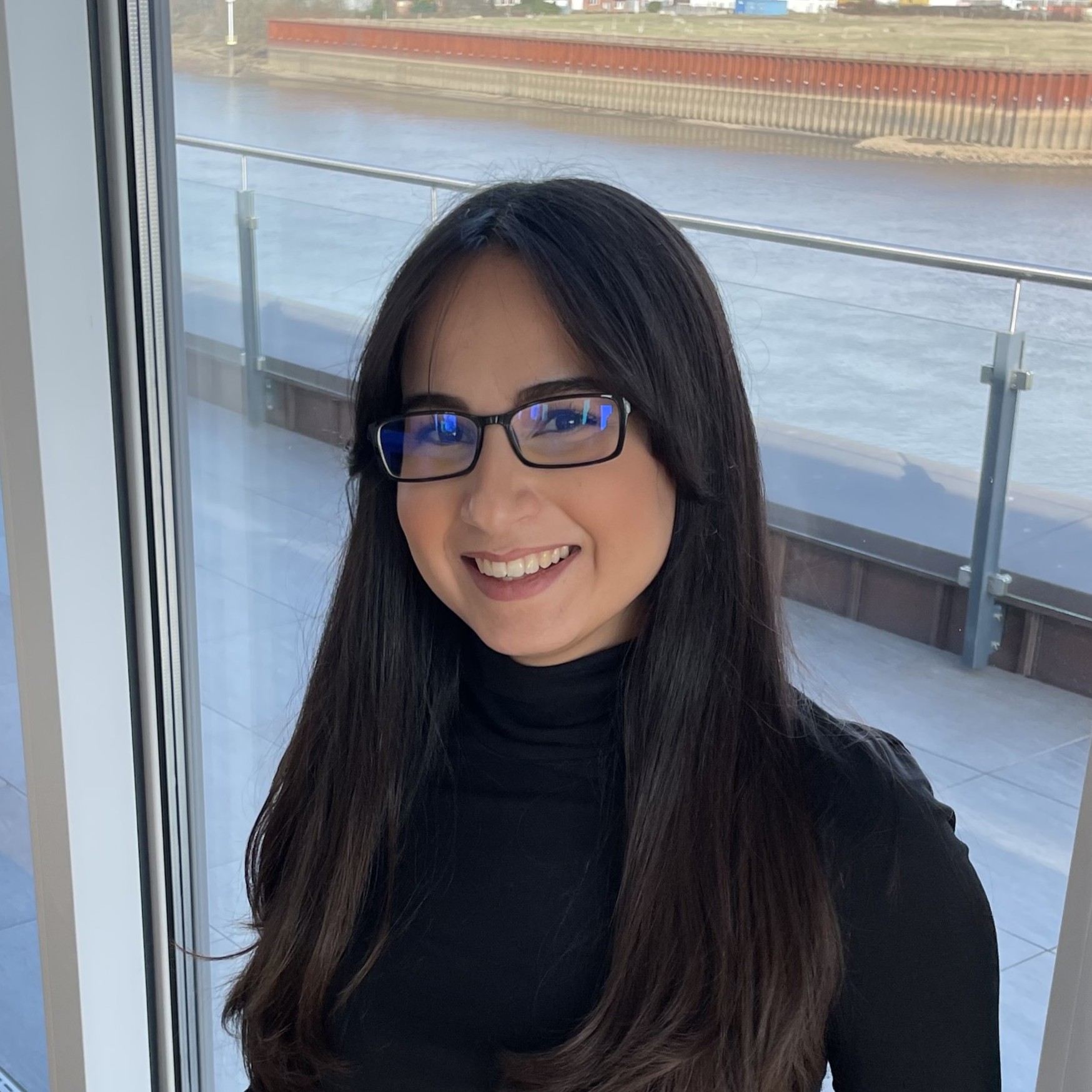  Portraitfoto von Hatice Erkekoğulları, Leiterin HR bei LWLcom. Sie hat lange braune Haare, eine Brille und trägt einen schwarzen Pullover vor unscharfem Hintergrund.