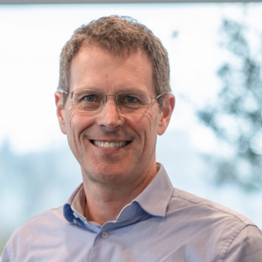 Geschäftsführer der LWLcom GmbH Frank Holmes. Er hat kurzes grau-blondes Haar, trägt ein hellblaues Hemd und steht vor einem unscharfem Hintergrund.